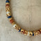 Necklace with gold, blue, and brown beads on a textured beige background