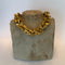 Gold necklace on a stone bust against a white background