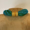 Green beaded bracelet with gold plated clasp on a textured surface