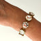 Gold bracelet with clear gemstones on a wrist against a white background