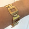 Gold bracelet on a wrist against a white background