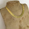 Gold necklace on a mannequin bust against a white background