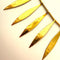 Gold leaf-like necklace on a light pink background