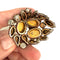 Vintage brooch with intricate design held by a hand on a white background