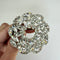 round sparkly clear stone brooch held in the hand