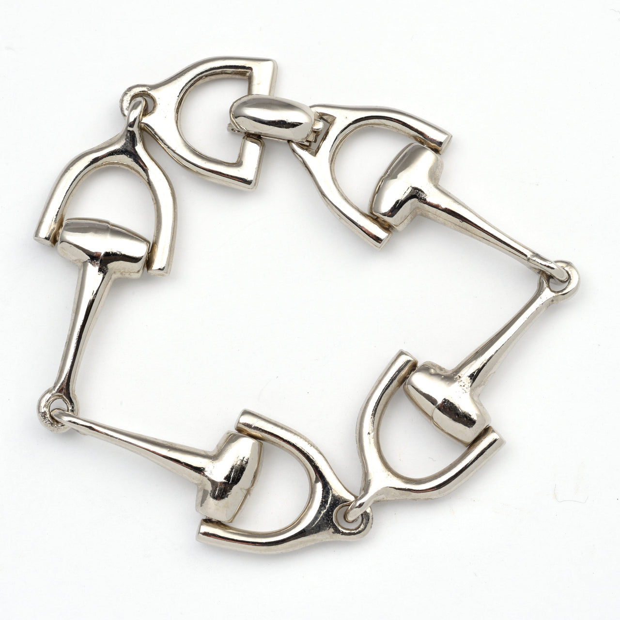 A silver horsebit link bracelet featuring four horsebit charms connected by metal rings, shown on a plain white background.