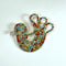 A colorful, handcrafted bead or rhinestone piece shaped like a stylized chicken, featuring a mix of red, blue, green, yellow, and gold-toned stones on a plain white background.