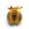 A gold-plated brooch in the shape of an apple, set with brown, topaz, and pale yellow crystals.