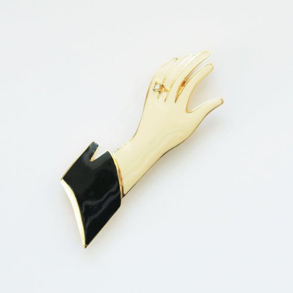 1980s vintage trifari hand brooch in black and cream enamel on a white background